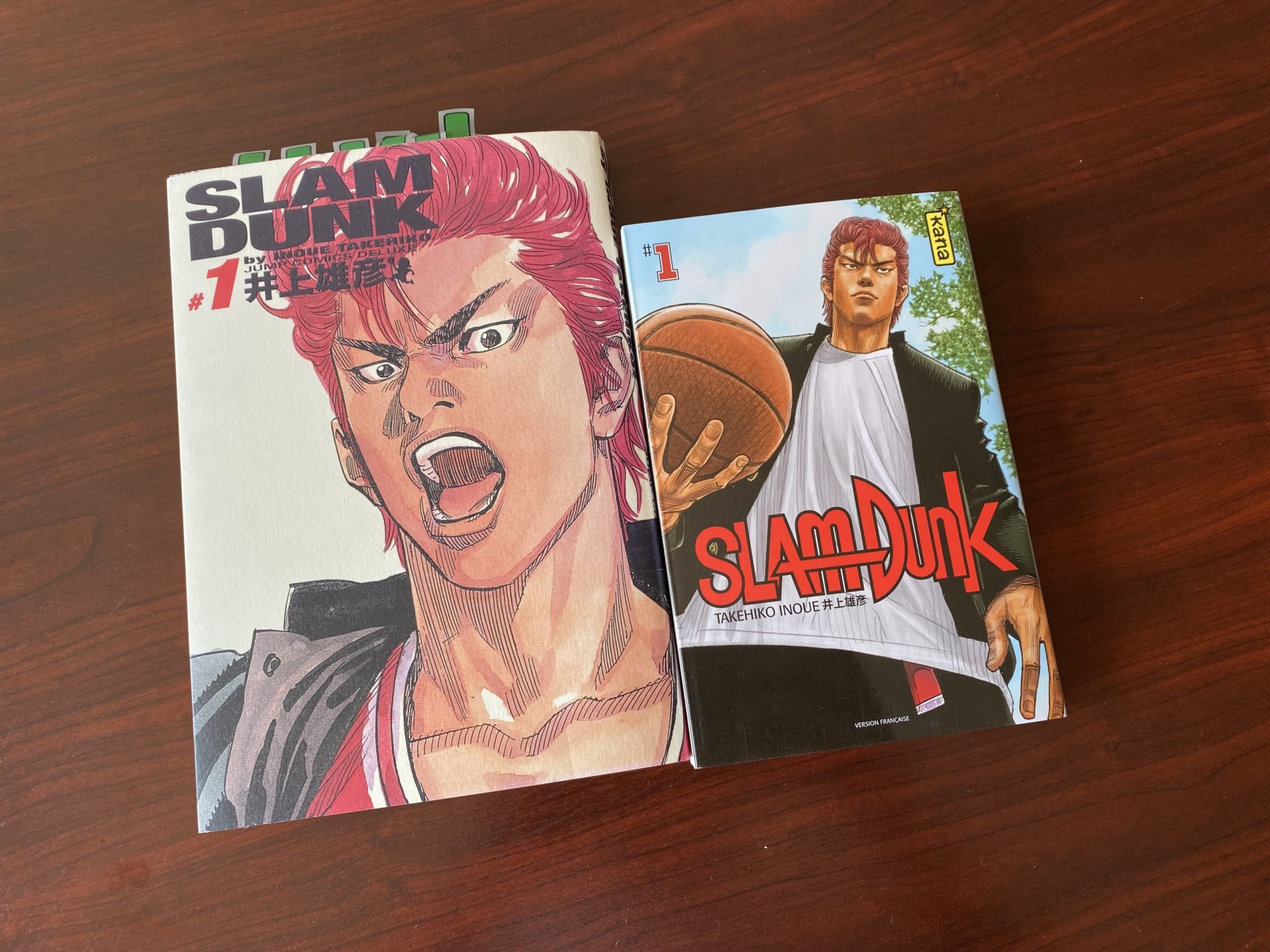 Photographie Kana montrant deux présentations de Slam Dunk, dont un exemplaire Deluxe japonais et un volume français
